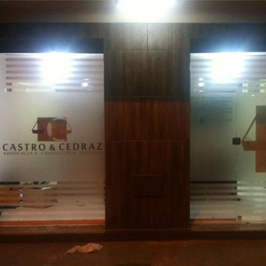 Os detalhes no vidro, como o emblema da logo, chamam atenção para a banca de Governador Valadares/MG, situada em uma sala empresarial.