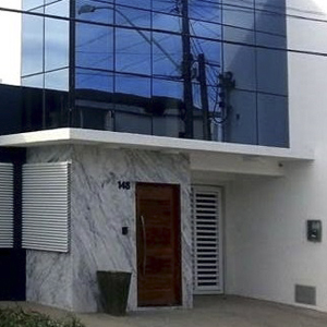Na ensolarada Maceió/AL, misturando mármore branco e vidro, a cor preta e a estrutura vazada em branco confere modernidade e sobriedade à fachada do escritório. 