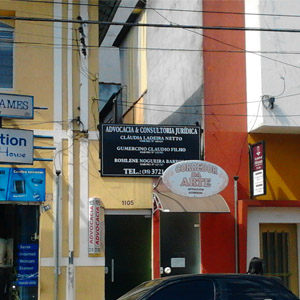 Em rua movimentada na Cidade das Fontes, Poços de Caldas/MG, a placa do escritório se destaca em meio a outras placas. 