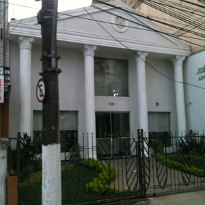 De dentro do bonde, na rua Brás Cubas, avista-se a fachada do grande escritório localizado no centro histórico de Santos/SP. 