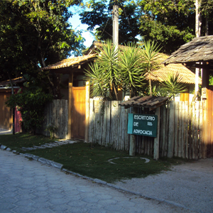 A calçada coberta de gramas e o cercado amadeirado compõe a arquitetura ecológica do escritório do povoado de Trancoso/BA. Complementando o cenário tropical, várias espécies de plantas. 