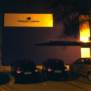 Na noite escura de Ribeirão Preto/SP, a sombra de um coqueiro realça a frente do grande escritório.