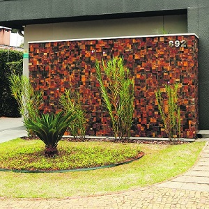 O paredão revestido de pedra ferro constrasta com o verde do jardim  realçando a fachada do escritório de Campinas/SP.